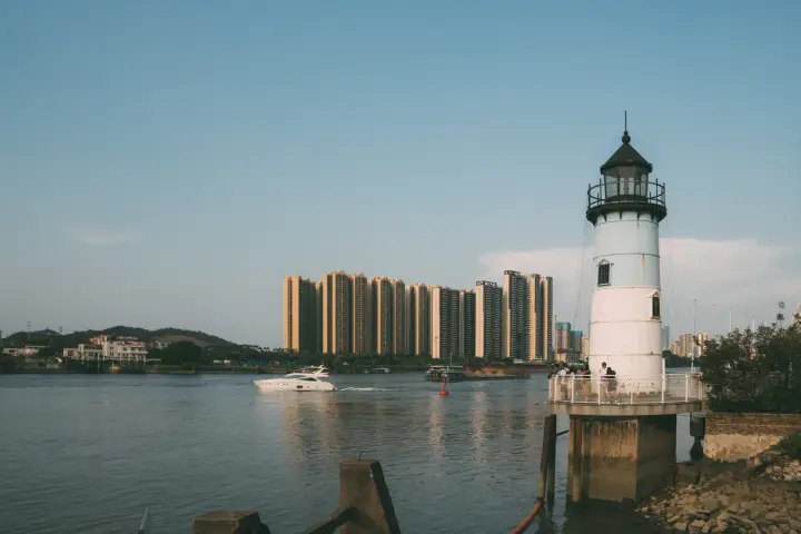 水边灯塔与远处楼群